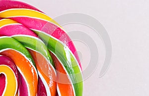 Bright rainbow round lollipop. On pink background.Copy space