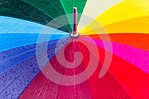 Bright rainbow umbrella covered with rain drops texture