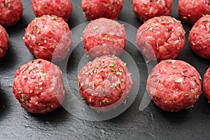 Bright raw meatballs on the background of dark basalt plate