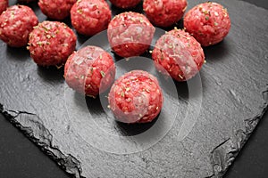 Bright raw meatballs on the background of dark basalt plate
