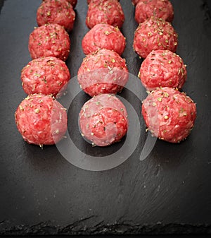 Bright raw meatballs on the background of dark basalt plate