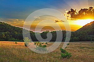Bright rays of the sunset break through the clouds at high mountains