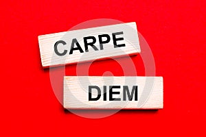 On a bright red background, there are two light wooden blocks with the text CARPE DIEM