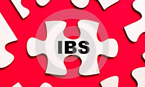 On a bright red background, white puzzles. In one of the pieces of the puzzle, the text IBS