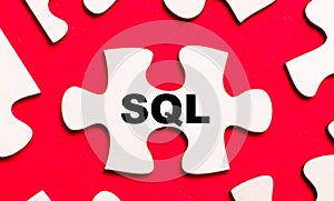 On a bright red background, white puzzles. In one of the pieces of the puzzle, the text SQL Structured Query Language