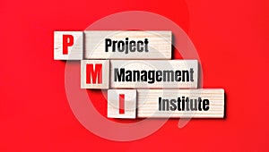 On a bright red background, wooden cubes and blocks with the text PMI Project Management Institute. Manufacturing of wooden toys