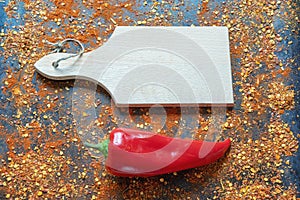 Bright red bell pepper and cutting board with crushed hot paprika scattered. Space for text