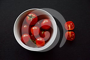 Bright Red Cherry Tomatoes, White Bowl, Two Red Half-fractions, Black Table