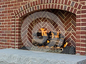 Cheerful fire burns in brick fireplace heating outdoor space