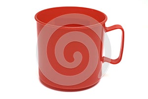 A bright red colored plastic mug cup with handle white backdrop