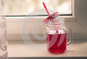 Bright red compote in the original glass mug, autumn composition on the window. Hugue style, autumn style, autumn still life