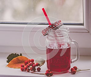 Bright red compote in the original glass mug, autumn composition on the window. Hugue style, autumn style, autumn still life