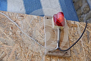 Bright red construction lamp lit with fence in background on entrance of construction site