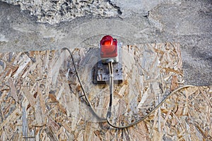 Bright red construction lamp lit with fence in background on entrance of construction site