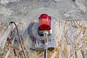 Bright red construction lamp lit with fence in background on entrance of construction site