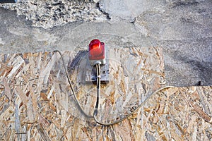 Bright red construction lamp lit with fence in background on entrance of construction site