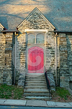 A Bright Red Door in a Cobblestone Church With Steps Leading Up to It