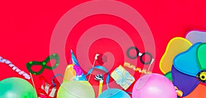 Bright red Festive background with party tools and decoration - baloons, funny carnival masks, festive tinsel. Happy birthday gree