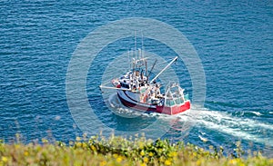 Bright red fishing boat heads out to sea from St. John's harbor Newfoundland, Canada.