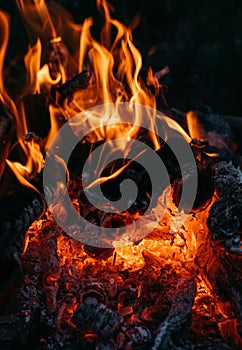 Bright red flames of fire. Ashes and coals. Flames on a dark background. Hot red hot coals, barbecue place. Outdoor