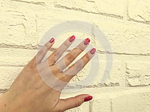 Bright, red, glossy manicure on an orange matte background. brick wall from plaster for shots of beauty services of masters. wall