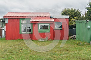 Bright red and green holiday home or batch in remote New Zealand coastal town