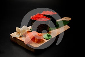 Bright red gunkan tobiko on a leaf with ginger and wasabi