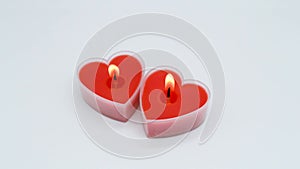 A bright red heart-shaped candle burns on a white background, but after a few seconds it is blown out and goes out. The concept of