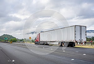 Bright red industrial long haul big rig semi truck with dry van semi trailer stands on the side of the road having made a planned