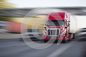 Bright red modern big rig semi truck with semi trailer move with