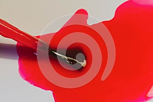 Bright red nail polish spilled on a white table