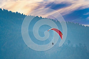 bright red para sailing being done in front of the majestic himalaya mountains in manali, bir, billing