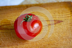 Bright red ripe tomato on a wooden board on the table