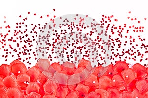 Bright red rose petals and hearts on a soft pink background. Layout for cards for Valentine`s day or wedding.