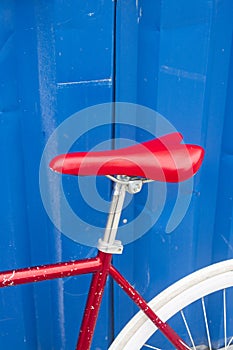 Bright red saddle of a bike against bright blue background of container