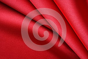 Bright red satin fabric with large folds, abstract background