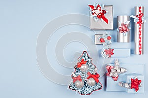 Bright red, silver and pastel blue christmas background of gift boxes and christmas tree with glitter balls with copy space.