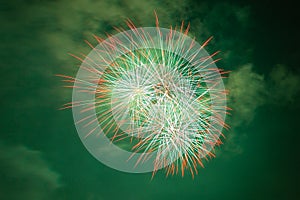 Bright red, white and green fireworks against the backdrop of the night sky