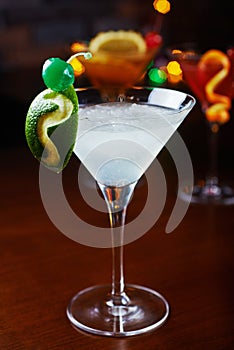 Bright refreshing cocktails: lime daiquiri on a table in a restaurant with creative decoration of lime slices and ice on a wooden