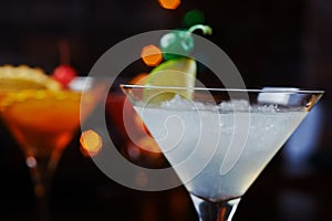 Bright refreshing cocktails: lime daiquiri on a table in a restaurant with creative decoration of lime slices and ice on a wooden