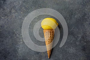 Bright Ripe Yellow Lemon in Waffle Ice Cream Cone on Dark Concrete Stone Background. Summer Fruits Dessert Freshness Vitamins