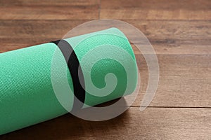 Bright rolled camping mat on wooden background, closeup. Space for text