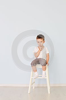 Bright room. Boy in white shirt sitting in a high chair