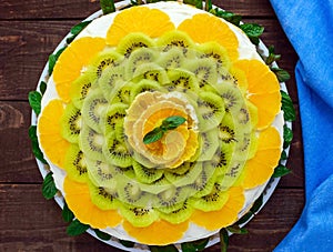 Bright round festive fruit cake decorated with kiwi, orange, mint