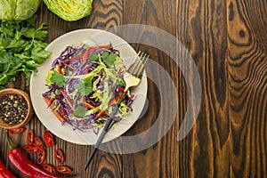 Bright salad of purple cabbage, white cabbage, bell pepper in a plate on a wooden table. Fresh vegetable salad. Food background.
