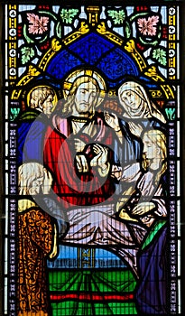 Stained glass window depicting Christ with sick woman.