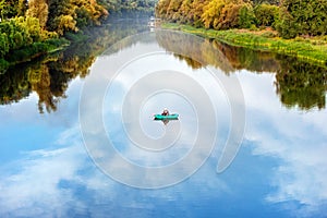 Bright scenic landscape of river in bright multicolored autumn forest with colorful trees. Blue sky reflection mirrored