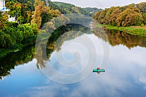 Bright scenic landscape of river in bright multicolored autumn forest with colorful trees. Blue sky reflection mirrored