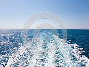 Bright sea water trail behind a cruise ship summer time. Ferry boat leaves a trail in a blue and clear water of