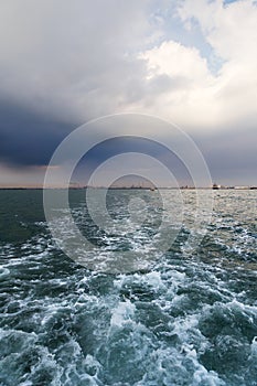 Bright sea water trail behind ship in Venice, Italy. Water bus leaves trail in green water in Venetian Lagoon leaving